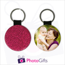 Load image into Gallery viewer, Two sides of a round keyring. On one side is a red glitter covering the whole keyring and on the other side is a picture of a grandmother holding a baby up to her face with some green trees blurred in the background. Keyring as produced by Photogifts.co.uk