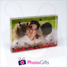 Load image into Gallery viewer, 152mm x 102mm (6&quot; x 4&quot;) clear acrylic freestanding block, in landscape orientation,  that can be personalised with your own choice of image. The block is filled with tiny red hearts suspended within a clear liquid. The chosen image is clipped to the back of the block and shows through so you can see it behind the liquid. When the block is shaken the red hearts will slowly make its way down to the bottom of the block similar to a snow globe
