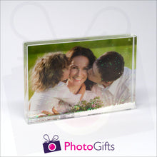 Load image into Gallery viewer, 152mm x 102mm (6&quot; x 4&quot;) clear acrylic freestanding block, in landscape orientation,  that can be personalised with your own choice of image. The block is filled with tiny snow flakes suspended within a clear liquid. The chosen image is clipped to the back of the block and shows through so you can see it behind the liquid. When the block is shaken the snow flakes will slowly make its way down to the bottom of the block similar to a snow globe
