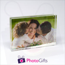 Load image into Gallery viewer, 152mm x 102mm (6" x 4") clear acrylic freestanding block, in landscape orientation, that can be personalised with your own choice of image. The block is filled with tiny snow flakes suspended within a clear liquid. The chosen image is clipped to the back of the block and shows through so you can see it behind the liquid. When the block is shaken the snow flakes will slowly make its way down to the bottom of the block similar to a snow globe