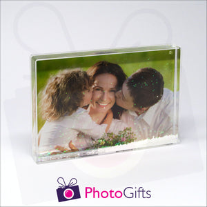 152mm x 102mm (6" x 4") clear acrylic freestanding block, in landscape orientation,  that can be personalised with your own choice of image. The block is filled with tiny snow flakes suspended within a clear liquid. The chosen image is clipped to the back of the block and shows through so you can see it behind the liquid. When the block is shaken the snow flakes will slowly make its way down to the bottom of the block similar to a snow globe