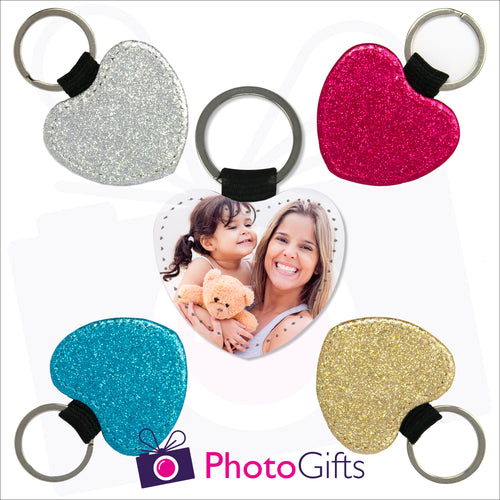Four glitter heart shaped keyrings surrounding a photo heart shaped keyring. Each of the glitter keyrings is a single coloured glitter in either red, blue, silver or gold. The central keyring shows the face of a mother holding a toddler and teddy bear. Also shown is the Photogifts logo. Keyring as produced by Photogifts.co.uk