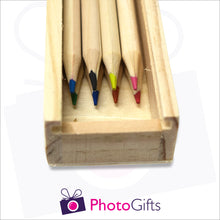 Load image into Gallery viewer, Close up of small wooden personalised pencil case showing slot where the top slides in and the 8 pencils that come with the box as produced by Photogifts.co.uk
