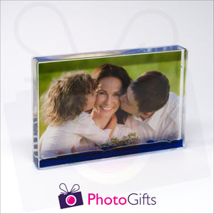 152mm x 102mm (6" x 4") clear acrylic freestanding block, in landscape orientation,  that can be personalised with your own choice of image. The block is filled with some blue gel suspended within a clear liquid. The chosen image is clipped to the back of the block and shows through so you can see it behind the liquid. When the block is shaken the blue gel will slowly make its way down to the bottom of the block similar to a snow globe