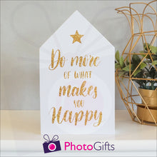 Load image into Gallery viewer, White wooden block in the shape of a house with the slogan &quot;Do more of what makes you happy&quot; printed on the front. The block is resting on a white shelf with a potted plant to one side. Personalised block as supplied by Photogifts.co.uk
