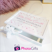 Load image into Gallery viewer, White wooden memory keepsake box with the personalisation of &quot;Ella Rose Smith Special Keepsakes 02.0422019 7lb 6oz 7:23pm&quot; printed on the box. The box is partially open and has a soft toy trapped by the lid. The box is sitting on a table with a picture frame and fluffy cushion in the background. Personalised box as supplied by Photogifts.co.uk 
