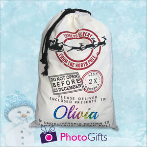 Blue snowy background with snowman with large white sack with the words "Express delivery from the north pole DO not open before 25 December Please delivery enclosed presents to Olivia if undelivered return to Santa Claus North Pole" by Photogifts.co.uk