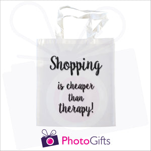 White tote shopping bag with the text "Shopping is cheaper than therapy!" printed in black on the bag